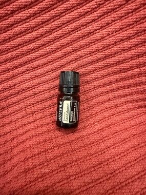 Doterra Sandalwood Essential Oil Bottle on Red Surface